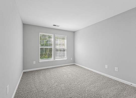 A room with a window and a carpeted floor.